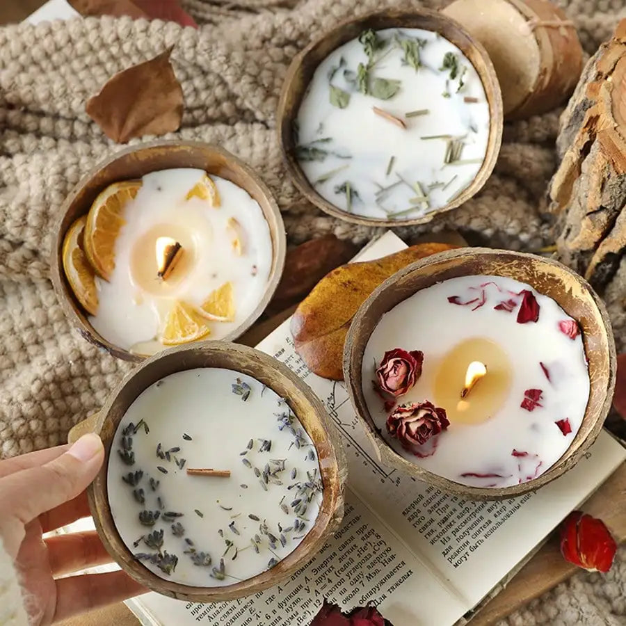 Four coconut wax candles in coconut shells with dried orange, lavender and rose toppings