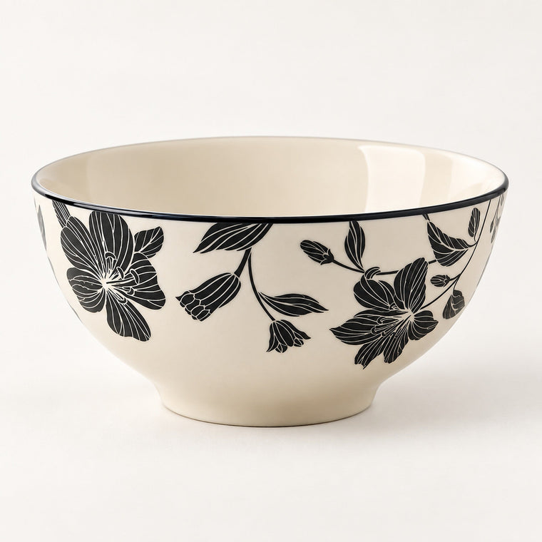 An off-white ceramic bowl featuring a black floral pattern on the exterior and a thin black rim, photographed against a