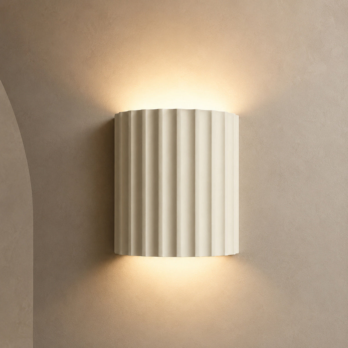Ivory fluted up down wall light glowing warm against a greige wall