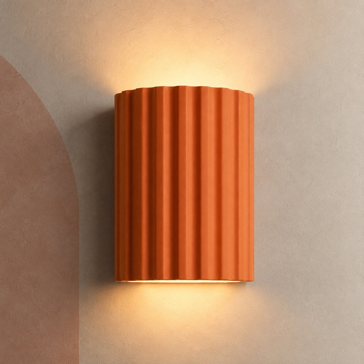 Terracotta ribbed wall sconce lit up and down on a plaster wall