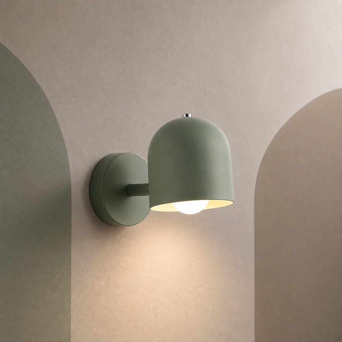 Green dome bedside wall sconce lit on a warm greige wall