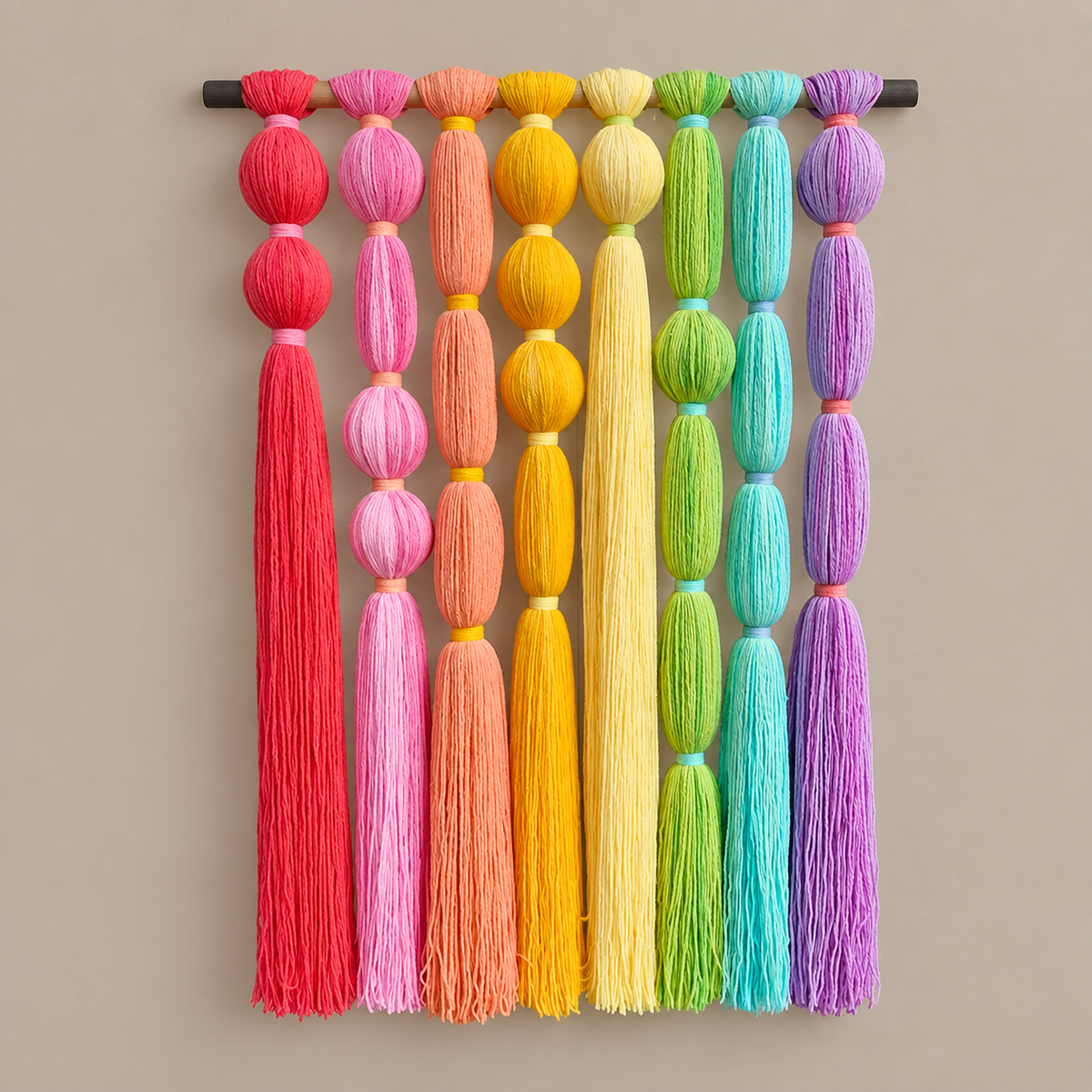 A studio on cream, rainbow tassel wall hanging, yarn-wrapped beads, fine cord tassels