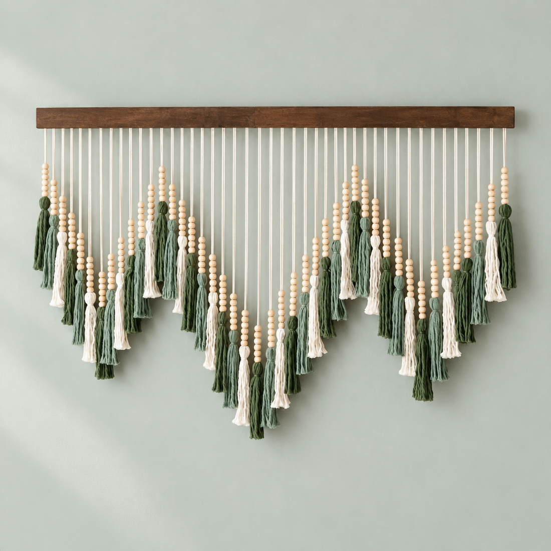 Sage and cream beaded tassels cut into three sharp peaks on a sage wall