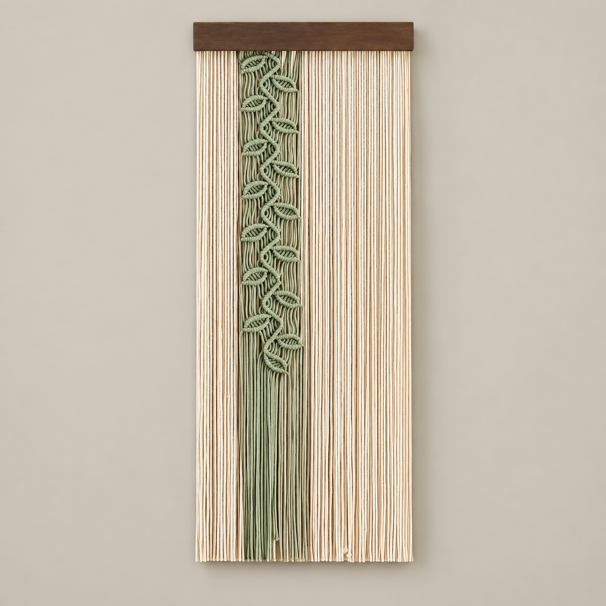 A vertical woven wall hanging with a natural wood top bar, featuring a central sage green leafy vine pattern over a