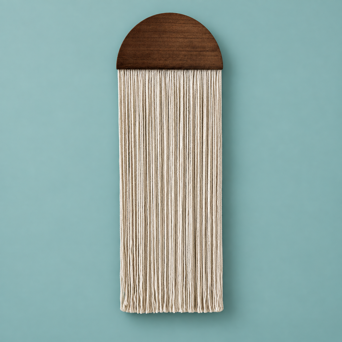 A vertical wall hanging with a dark brown wooden semicircular top and long cream-colored fringe strands, shown against a