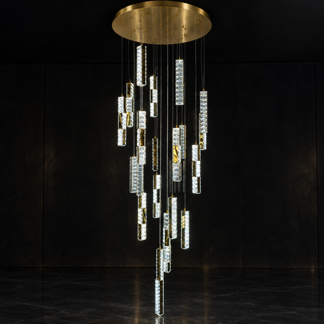 A modern multi-light chandelier with a circular brushed gold ceiling canopy and multiple cascading clear cylindrical crystal prisms, shown against a dark black background.