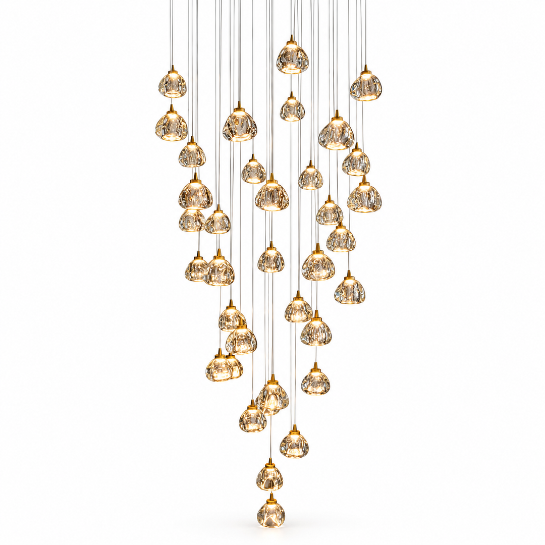 A modern multi-light pendant chandelier with multiple teardrop-shaped clear glass droplets featuring a gold crackle or textured finish, suspended from thin cables in a cascading, V-shaped arrangement against a solid white background.