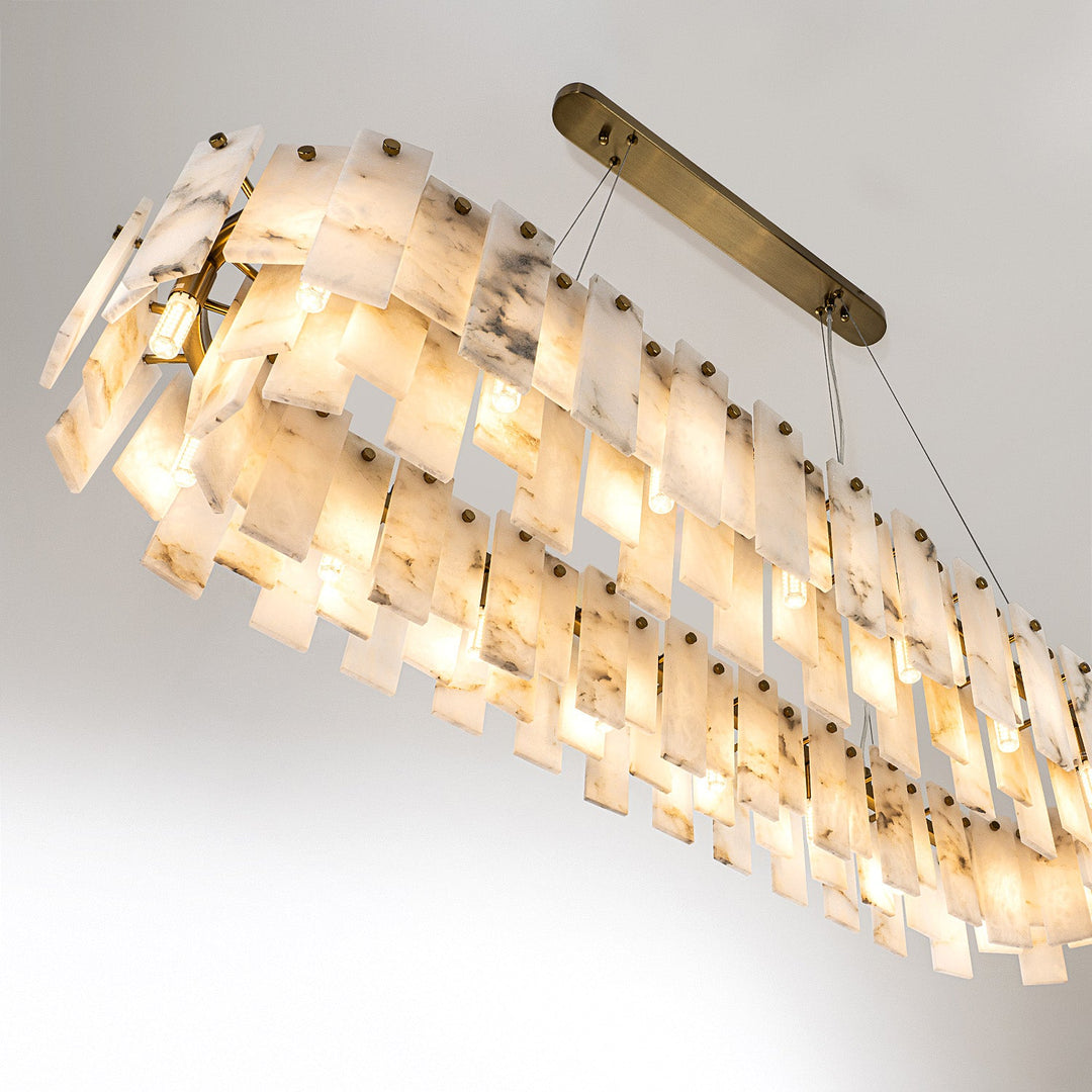 Pendant light viewed from below, showing illuminated alabaster panels, visible bulbs, suspension cables and a gold-colored ceiling canopy.