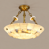 A vintage-style semi-flush mount ceiling light fixture with a gold brass metal frame, a large circular shade made of cream-colored marbled glass panels, and two white glass shades at the top, suspended by chains against a plain beige background.