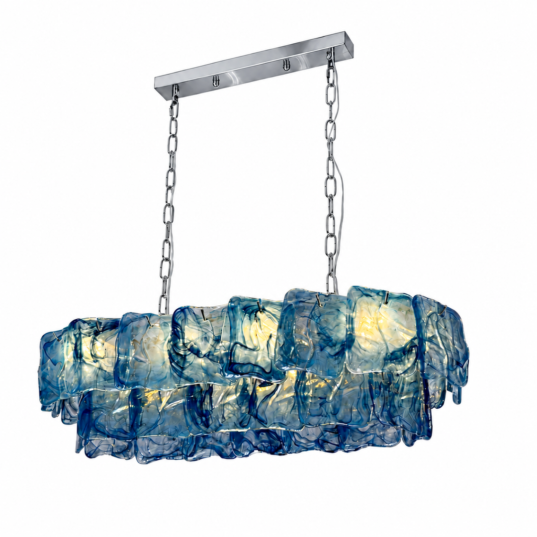 A linear chandelier with overlapping blue textured glass panels hangs from silver chains against a white background.