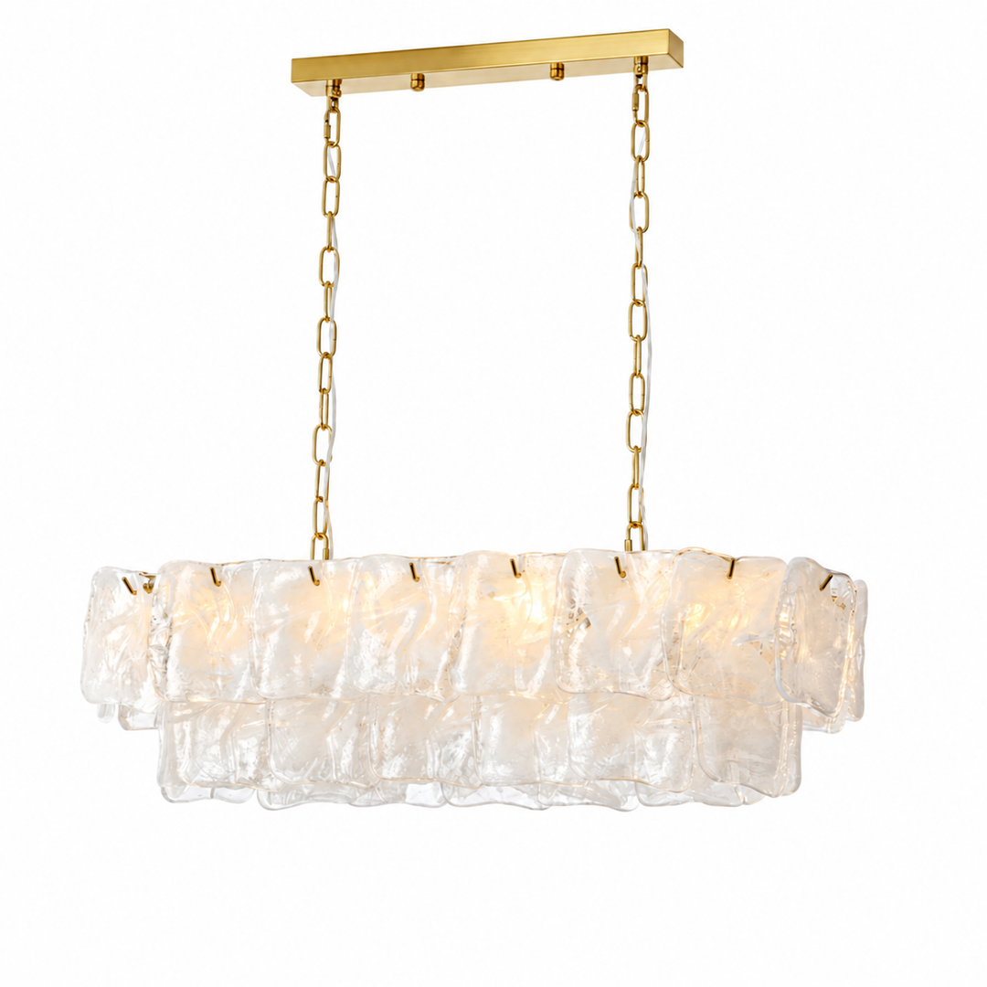 A linear chandelier with two tiers of clear textured glass hangs from gold chains against a white background.