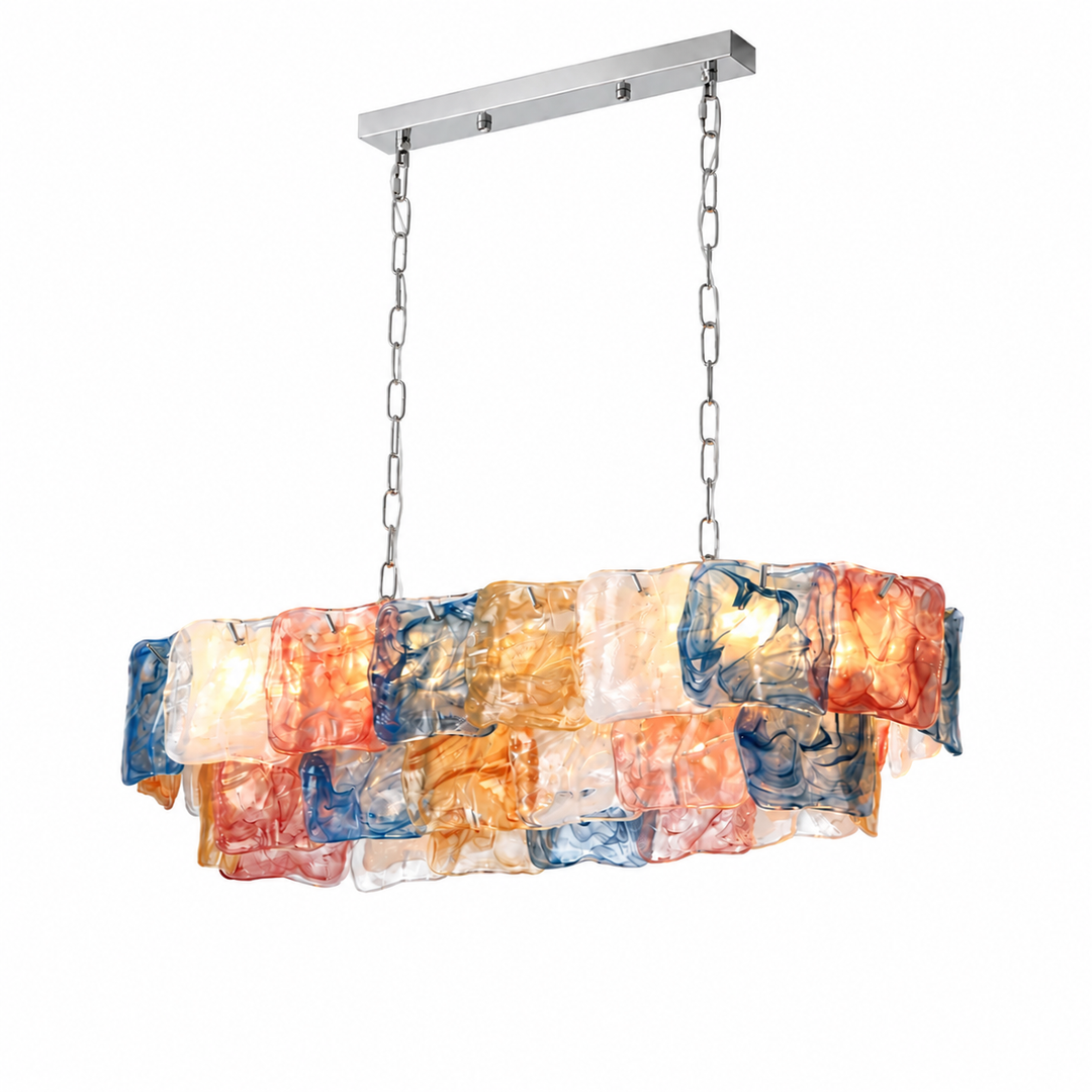 Linear chandelier with layered multicoloured textured glass panels hangs from silver-toned chains and a matching ceiling canopy against a white background.
