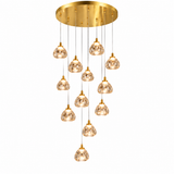 A modern multi-light chandelier with a circular gold brass ceiling canopy and ten cascading clear glass pendant shades on thin cords, shown against a plain white background.