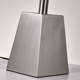 Close-up of the floor lamp’s tapered brushed silver base and cylindrical stem, with a black cord visible against a pale background.