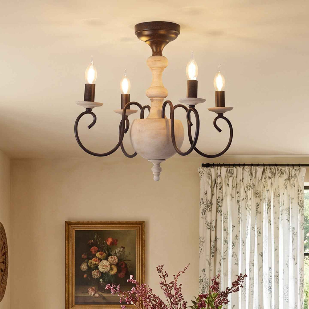 A rustic six-light chandelier with a distressed dark metal scrollwork frame and a central cream-colored wooden column, shown hanging on a beige ceiling in a decorated room with curtains and a framed painting.