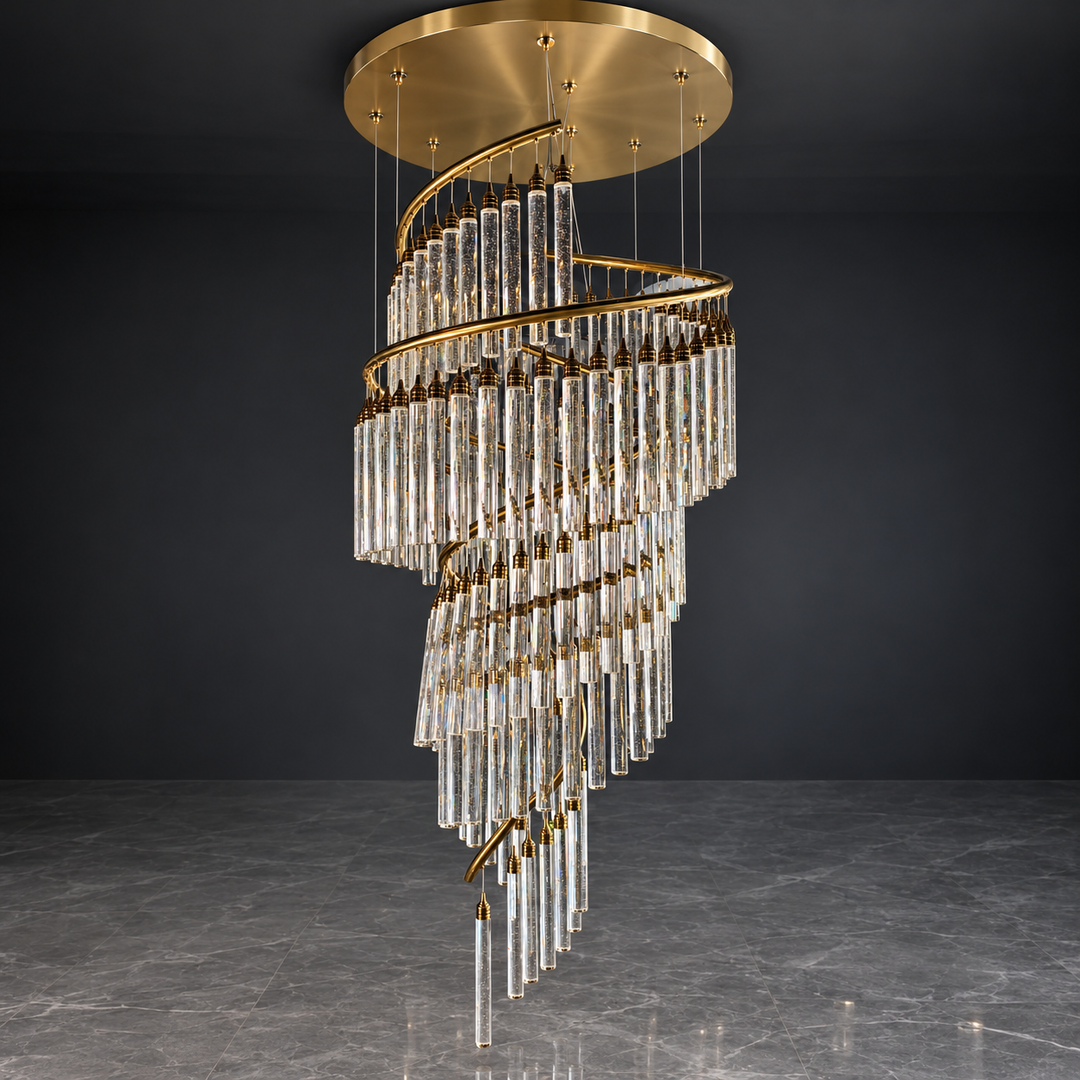 A modern spiral chandelier with clear glass cylindrical tubes and gold metal accents, suspended from a circular gold ceiling canopy against a dark gray wall and floor.