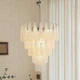 Chandelier hanging in a room with curtains and a wall art piece.