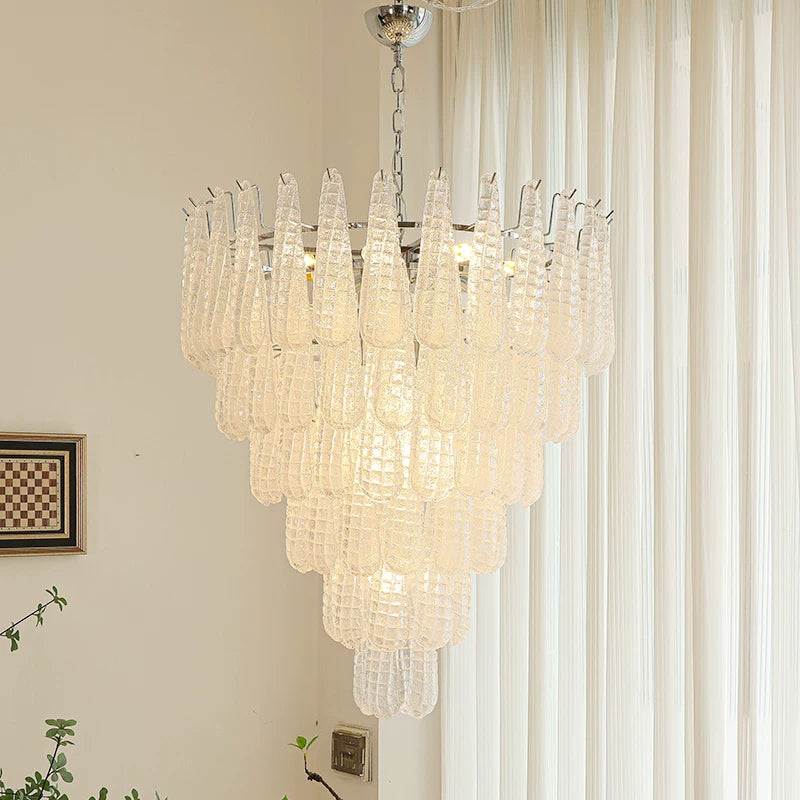 Chandelier hanging in a room with curtains and a wall art piece.