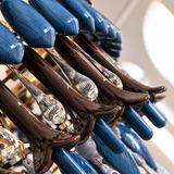 Close-up of a chandelier with glossy blue and dark brown petals and clear ribbed glass drops against a pale background.