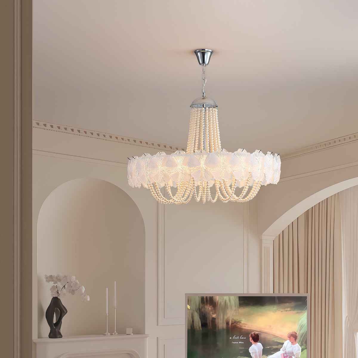 A multi-tiered chandelier with a white ruffled flower-like shade and hanging pearl beads, suspended from a silver ceiling canopy in a cream-colored room.