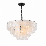 A modern multi-tier chandelier featuring textured, irregular clear glass panels suspended from a black metal frame, chain, and ceiling canopy, shown against a plain white background.
