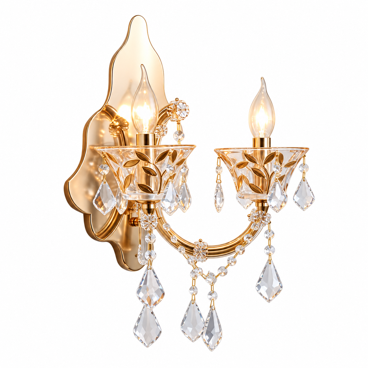 A two-light wall sconce with a polished gold-tone metal frame, leaf-like wall mounting, clear faceted crystal drops, and lit bulb-shaped lights, shown on a plain white background.
