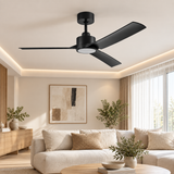 A matte black three-blade ceiling fan with an integrated light fixture, shown installed on the ceiling of a modern, warm-toned living room with beige sofas, plants, and window light.