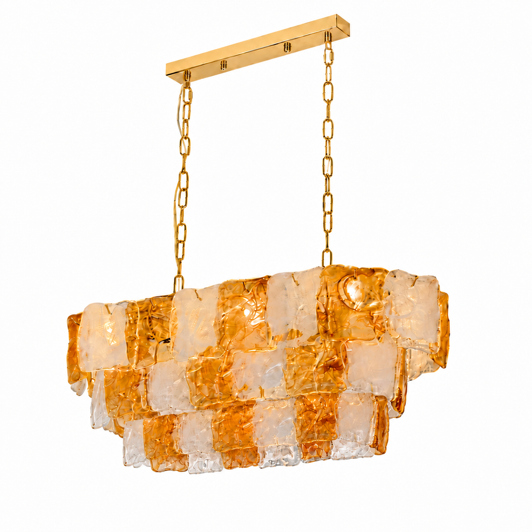 Linear chandelier with tiered amber and clear textured glass panels, gold-toned chains and a matching ceiling canopy against a white background.