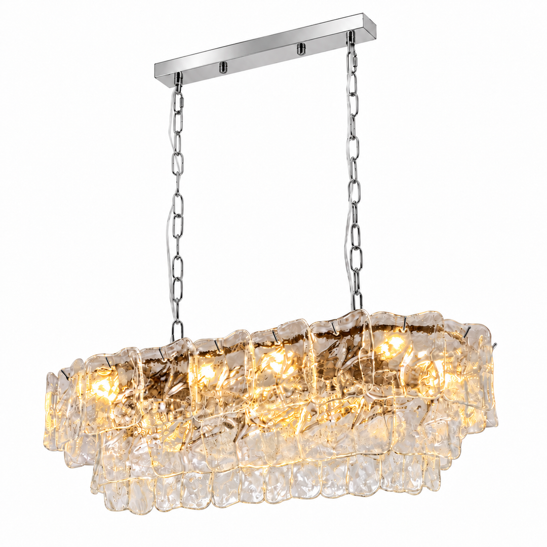 Linear chandelier with tiered clear textured glass, silver-tone chains and canopy, and glowing lights against a white background.