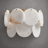 Wall sconce with white alabaster discs, subtle brown veining and brass fittings against a gray wall.