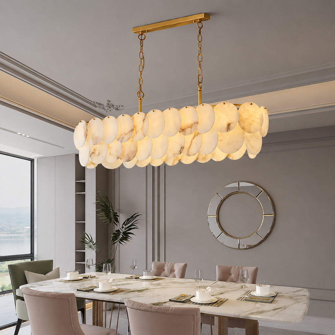 Brass linear chandelier with glowing alabaster discs hangs above a long dining table in a grey dining room.