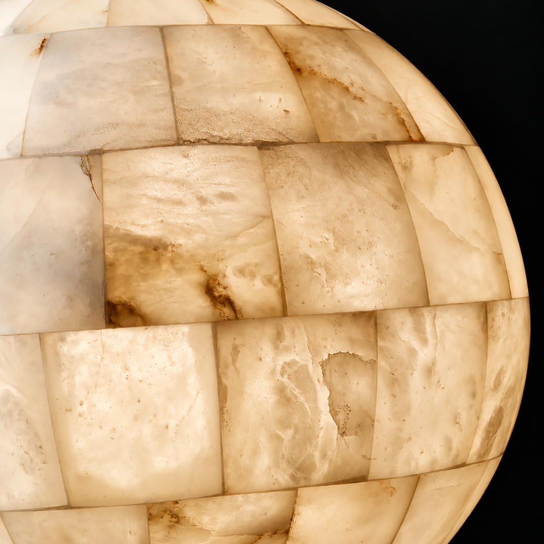 Close-up of a pendant light’s ivory alabaster globe, showing rectangular stone sections and natural veining against a black background.