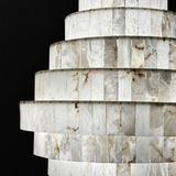A close-up of a tiered chandelier or lampshade made from stacked rectangular onyx or marble panels with natural white, gray, and tan veining, set against a solid black background.