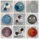 Chandelier glass globes in a nine-panel collage showing blue, clear, smoky grey, purple and orange designs against pale backgrounds.