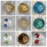 Chandelier glass globes in a nine-panel collage showing amber, blue, teal and clear designs with coloured openings against pale backgrounds.