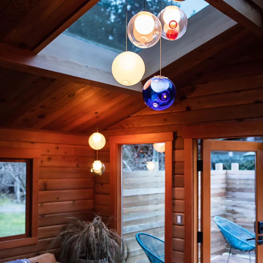 Chandelier with clear, white, and blue glass globes hanging beneath a skylight in a wood-paneled room.
