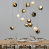 Chandelier with smoky and pale glass globes suspended above a wooden dining table surrounded by curved wooden chairs.