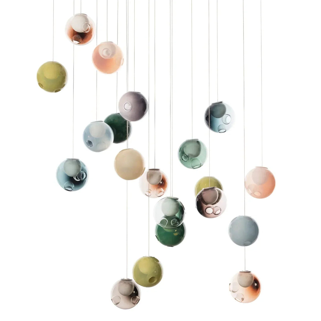 A chandelier with green, blue, pink, and smoky glass globes hangs at staggered heights against a white background.