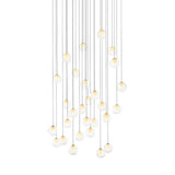 A chandelier with clear glass globes and glowing white centers hangs from long cords at varied heights against white.