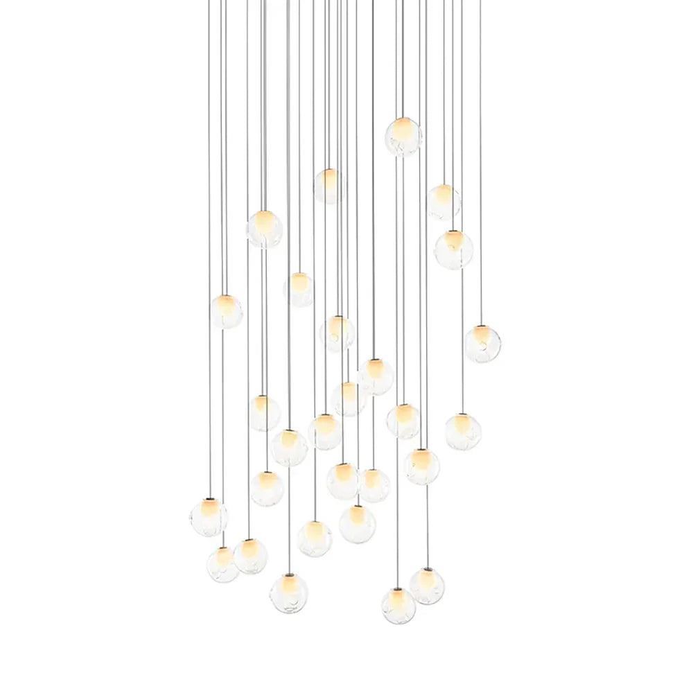 A chandelier with clear glass globes and glowing white centers hangs from long cords at varied heights against white.