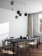 A chandelier with clear and smoky glass globes hangs above a black dining table beside a large window.