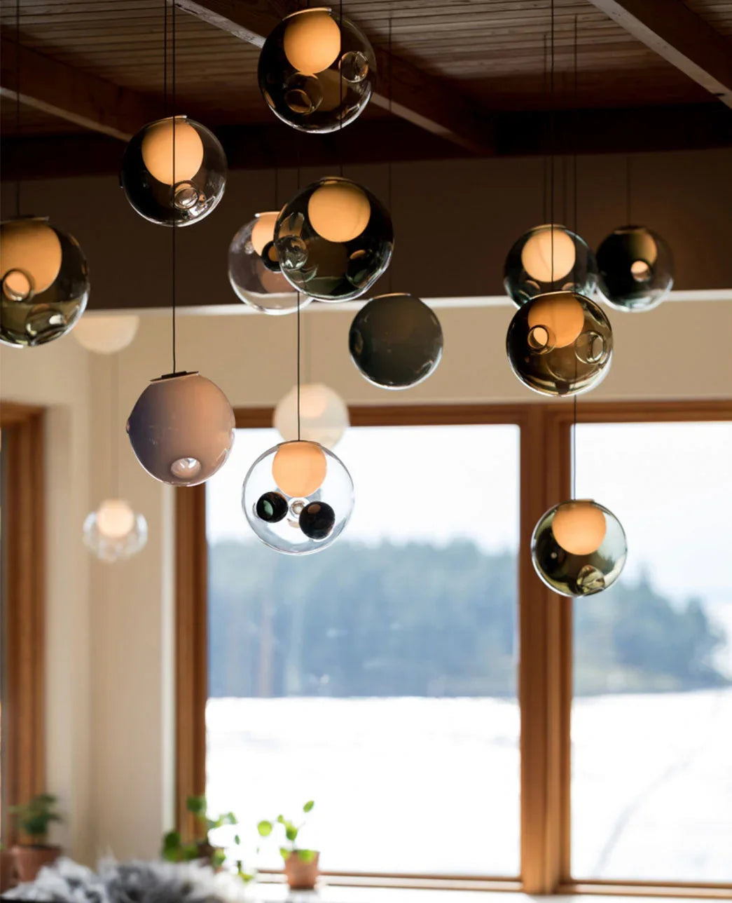 Chandelier of smoked and clear glass globes hanging at different heights in a bright room with large windows