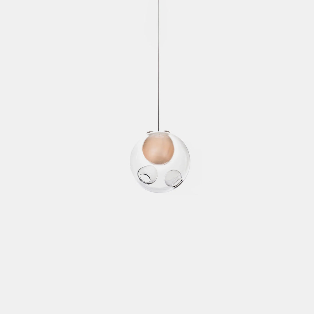 Single-globe chandelier with clear glass surrounding a peach-colored inner sphere, suspended from a thin cord against a white background.