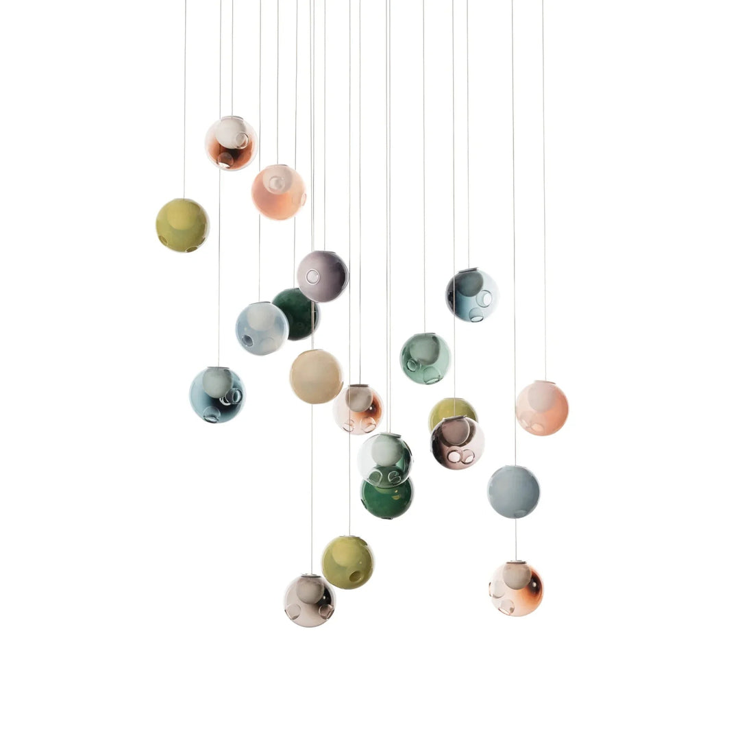 Unlit chandelier with green, pink, blue-gray, amber, and clear glass globes hanging at varied heights against a white background.