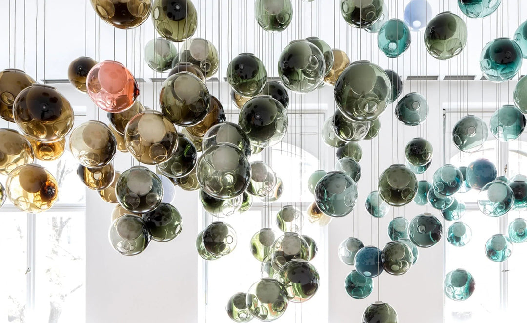 Colorful glass bubble chandelier hanging in a room with large windows.