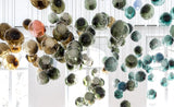 Colorful glass bubble chandelier hanging in a room with large windows.