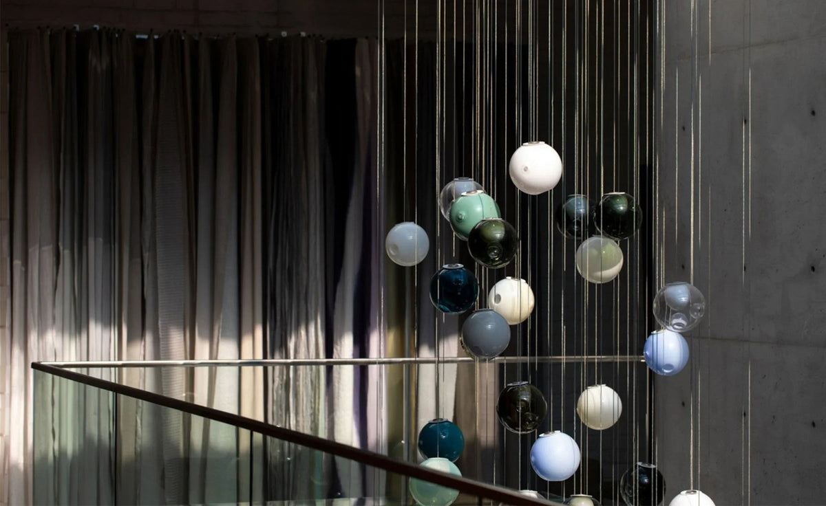 Modern chandelier with colorful glass balls hanging from a staircase.
