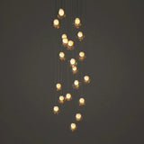 A modern multi-light linear chandelier with multiple warm glowing glass shades suspended at varying heights against a dark gray background.