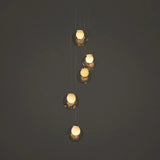 A modern multi-light pendant chandelier with five staggered, spherical glass globes suspended by thin cables against a dark gray background.