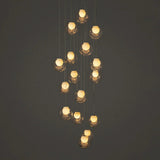 A modern multi-light pendant chandelier with multiple faceted clear glass globes suspended at varying heights against a dark gray background.